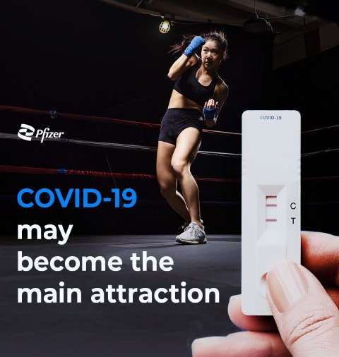 A person in boxing attire is in a fighting stance inside a boxing ring. In the foreground, a hand is holding a COVID-19 test strip showing a positive result. The text "COVID-19 may become the main attraction" is displayed on the left side of the image. The Pfizer logo is positioned above the text.